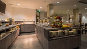 A modern hotel breakfast area with a buffet setup, including a variety of fruits and beverages. - Hotel Fortuna (Schwaebisch Gmuend)