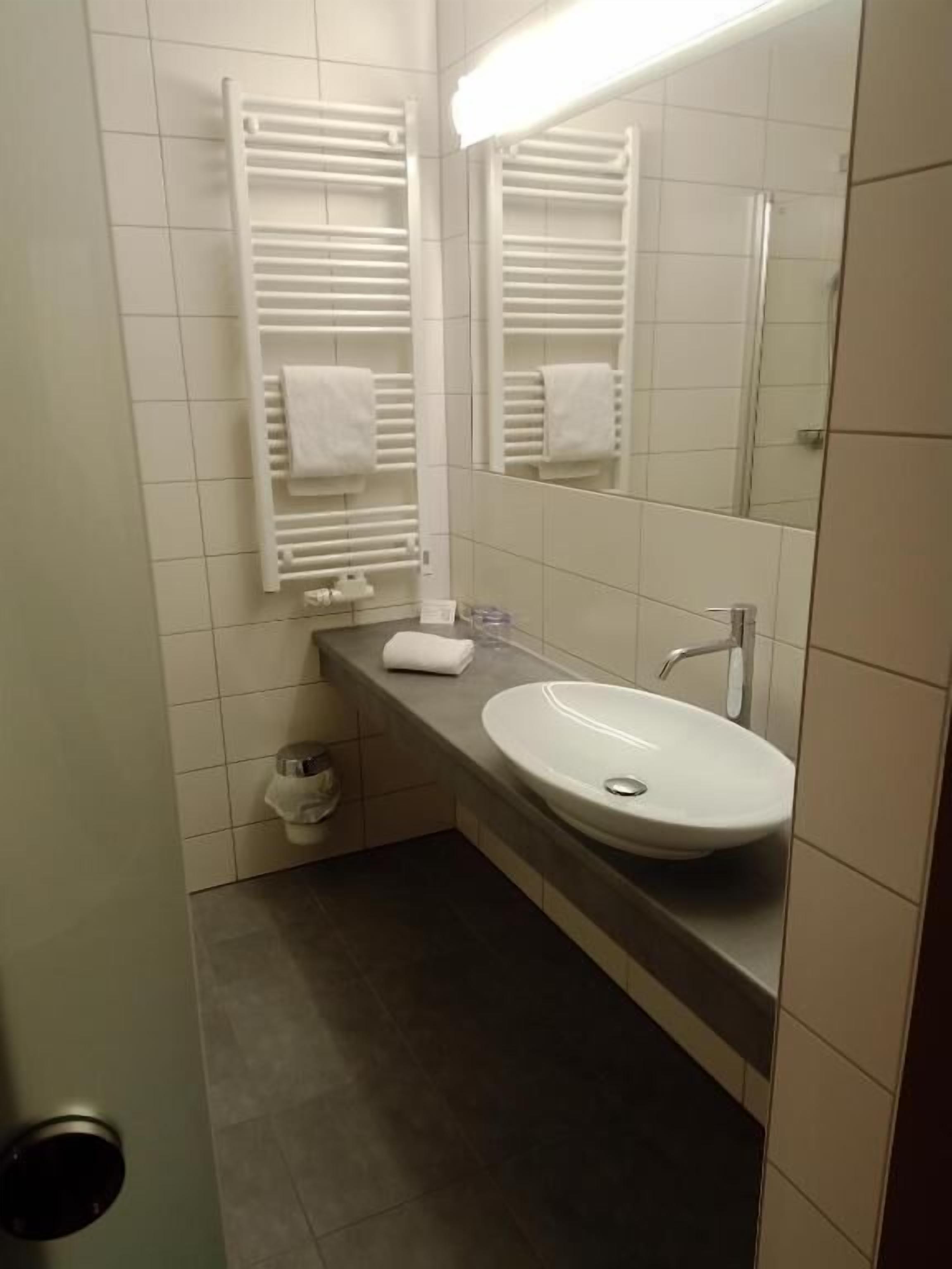 A bathroom with a white sink, a mirror, and a towel rack.
