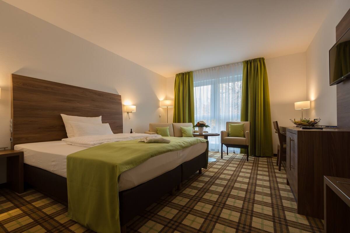 A hotel room with a bed, a desk, a chair, and a TV.