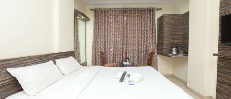 Una camera d'albergo con un letto grande, una televisione a schermo piatto montata a parete e un tavolino con un bollitore e tazze.