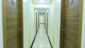 Un pasillo largo y estrecho con puertas de madera a ambos lados y un piso brillante.