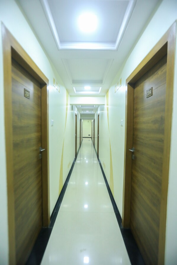 A long, narrow hallway with wooden doors on both sides and a shiny floor. - Hotel Midtown Andheri (Mumbai)