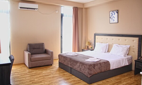 Una habitación de hotel con una cama, una silla, un escritorio y un equipo de aire acondicionado.