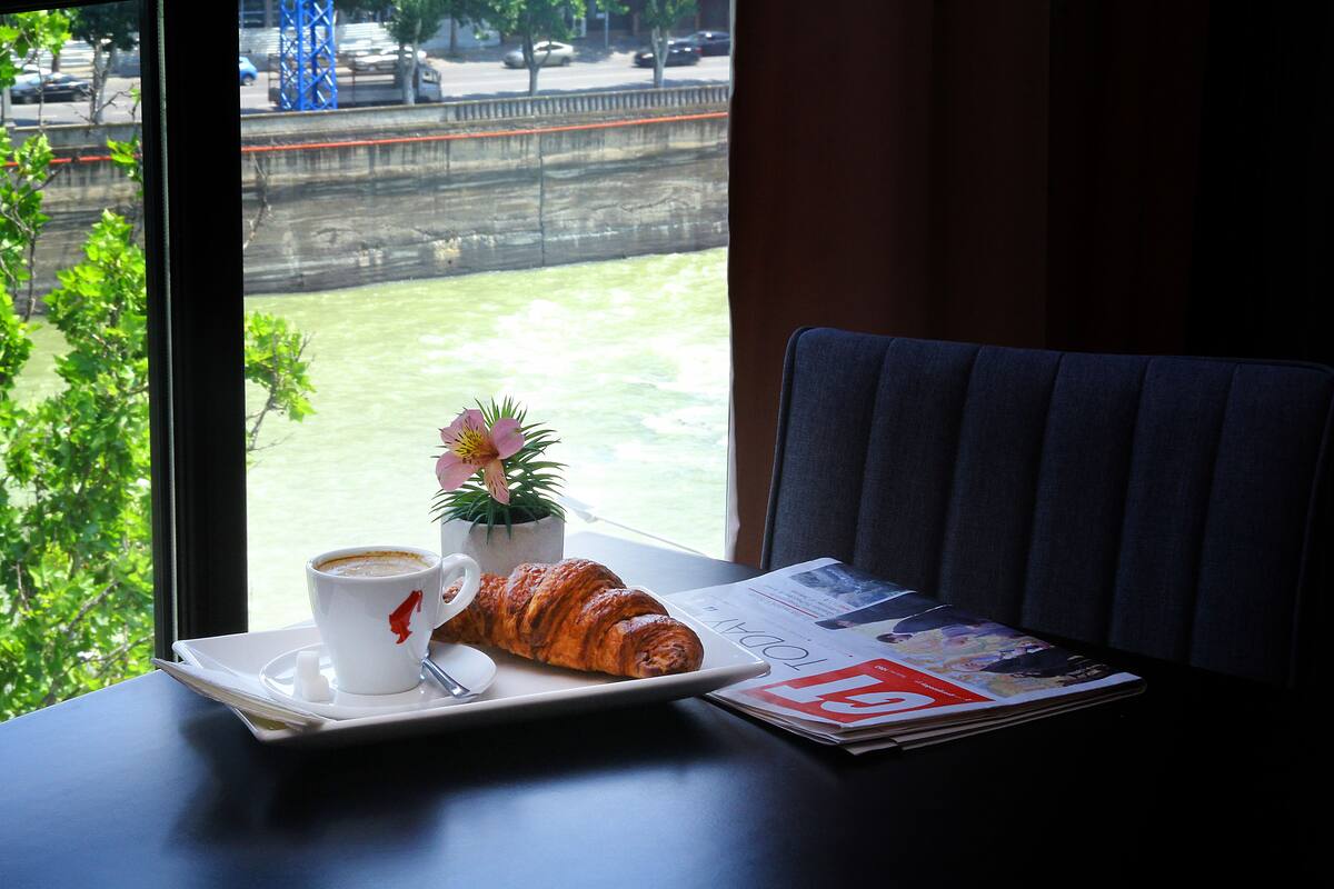 A table with a croissant, a cup of coffee, and a small potted plant.