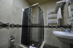 Un baño moderno con ducha envuelta en cristal, un lavabo y un perchero para toallas.