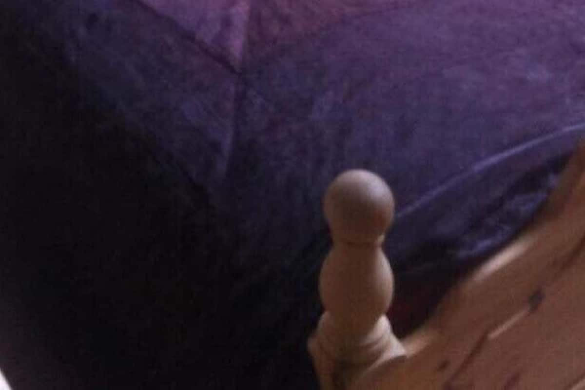 Una cama con cabecera de madera y colcha morada.