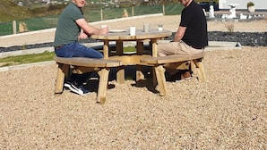Two people sitting at a wooden table outdoors with a house and mountains in the background. - Slieve League House B&B (Carrick)