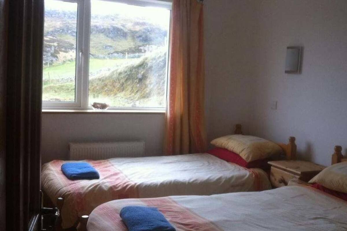 Una habitación con dos camas, una ventana con vistas al exterior y un radiador.