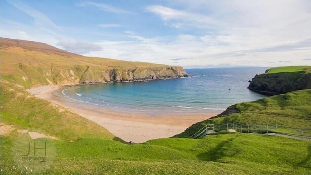 A coastal landscape with a sandy beach, grassy hills, and a clear sky. - Slieve League House B&B (Carrick)