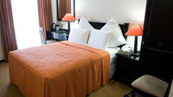 Une chambre d’hôtel avec un grand lit, deux tables de chevet, une chaise et un bureau avec une lampe.