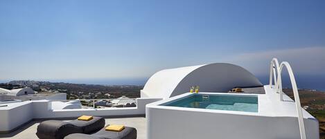 Una terraza en la azotea con piscina, sillones de descanso y vistas a la costa.