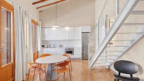 Une cuisine moderne avec des meubles blancs, un réfrigérateur en acier inoxydable et un coin repas comprenant une table ronde et des chaises.