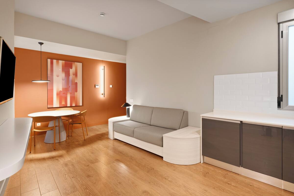 Una sala de estar moderna con sofá, mesa de comedor y zona de cocina.
