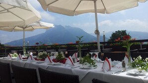 A table set for dining with white tablecloths, red napkins, and glassware, overlooking a mountainous landscape. - Hotel Kuehbergalp (Blaichach)