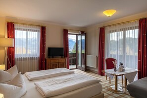 A hotel room with a bed, a desk, a chair, a table, and a television. - Hotel Kuehbergalp (Blaichach)