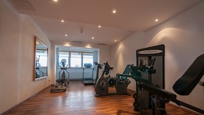 Un gimnasio con máquinas de cardio, una cinta de correr y un banco para pesas.