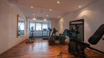 Un gimnasio con máquinas de cardio, una cinta de correr y un banco para pesas.