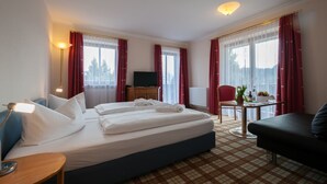 Habitación de hotel con cama, escritorio, silla, televisor y una mesa con planta.