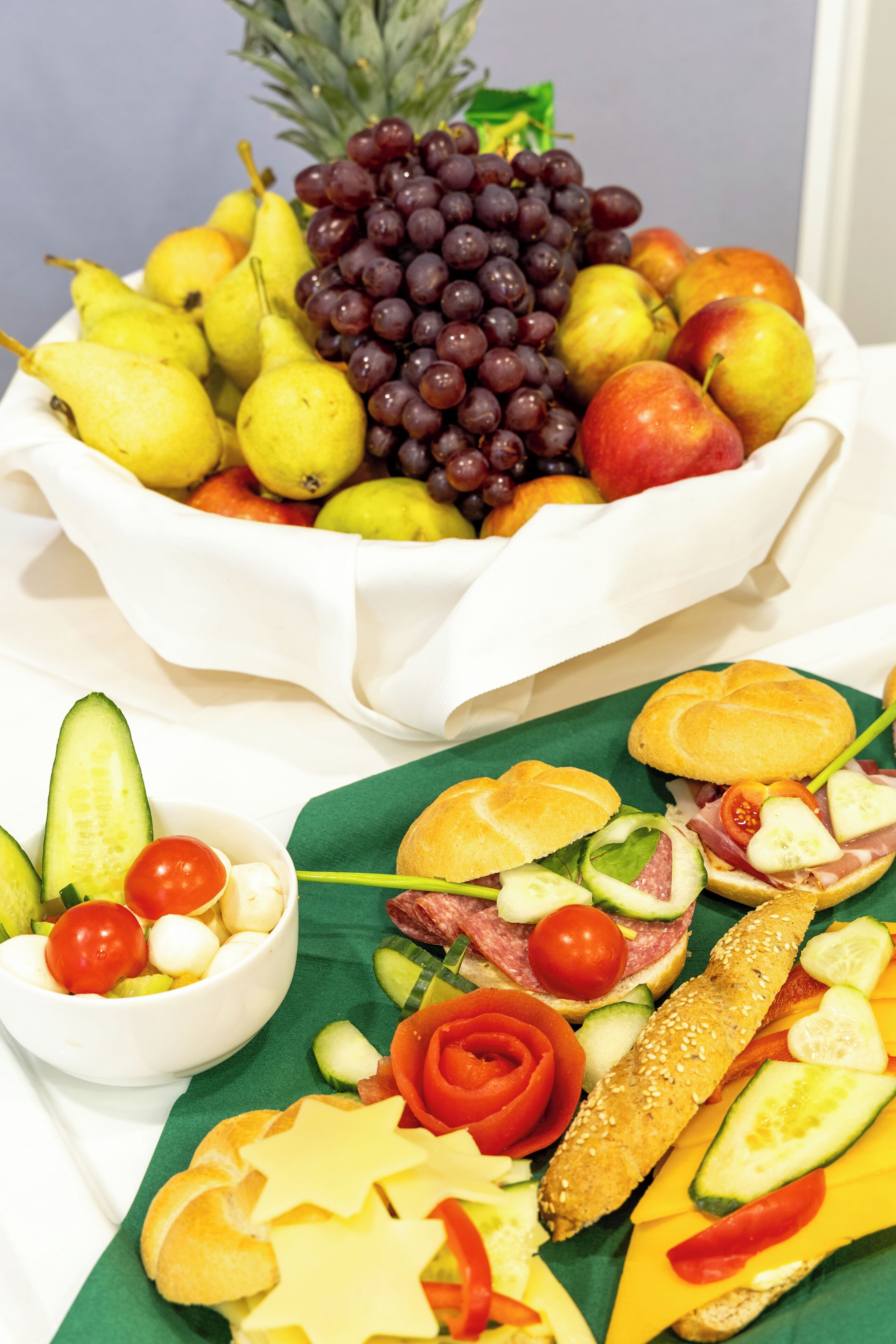 Un piatto di frutta e verdura con diverse varietà, tra cui uva, pere, mele e una ciotola di pomodorini ciliegino.