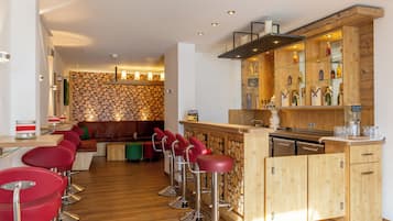 Un área de bar moderna con detalles de madera, taburetes rojos y una variedad de bebidas a la vista.