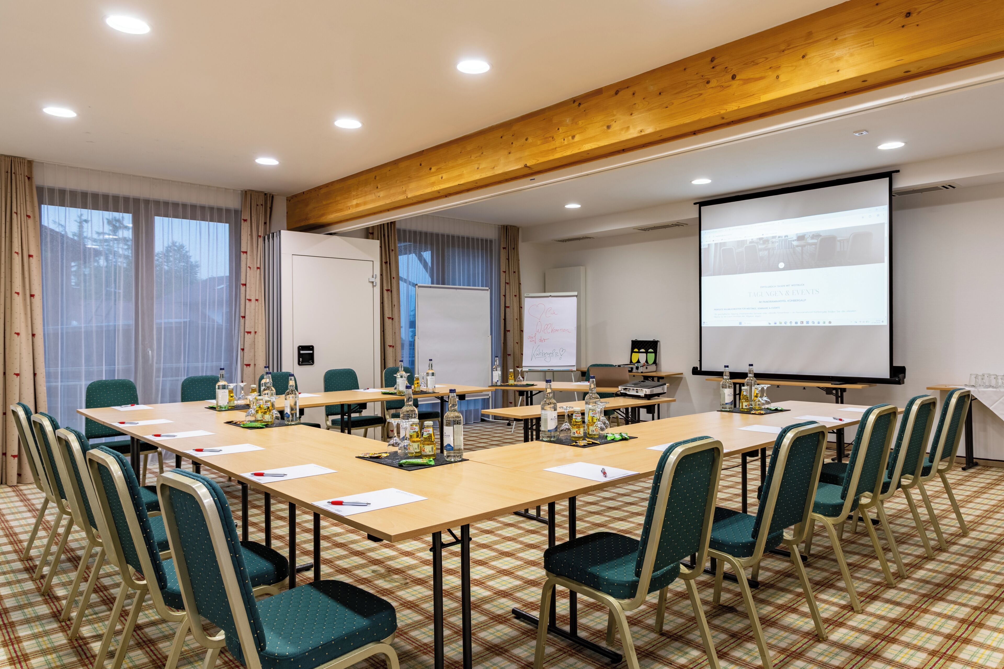 A conference room with a large table, chairs, a projector screen, and a whiteboard.