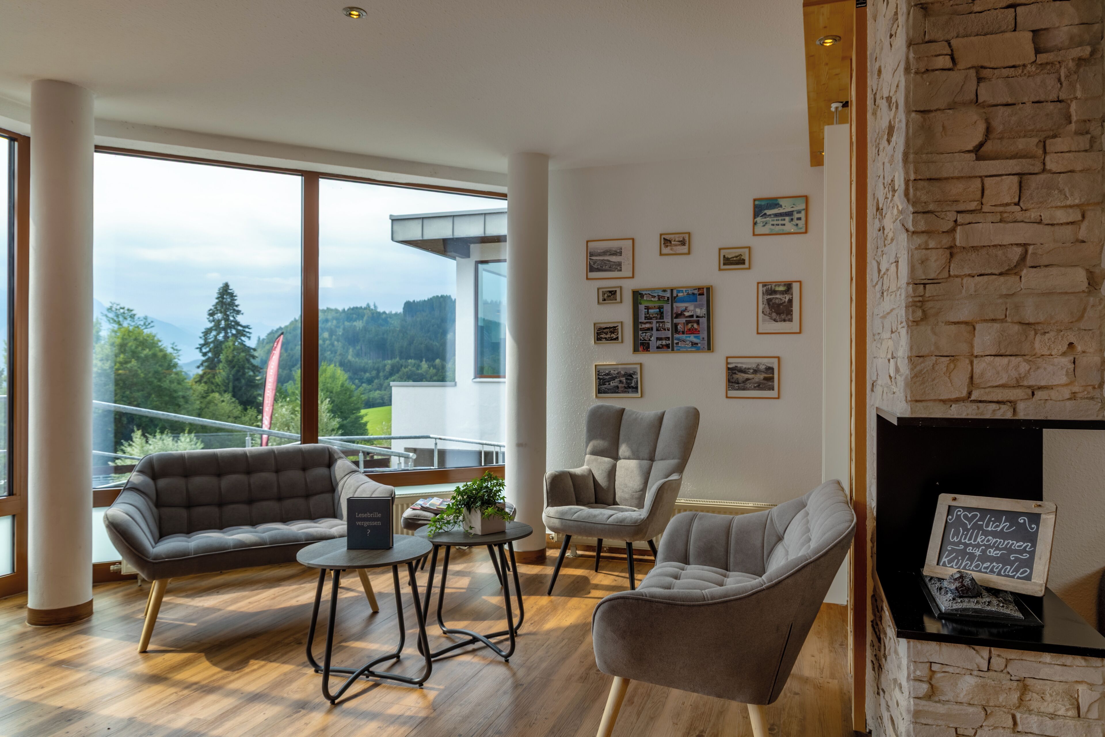Ein modernes Wohnzimmer mit einer Couch, Sesseln und einem Couchtisch. An den Wänden befinden sich gerahmte Bilder und ein Kamin.