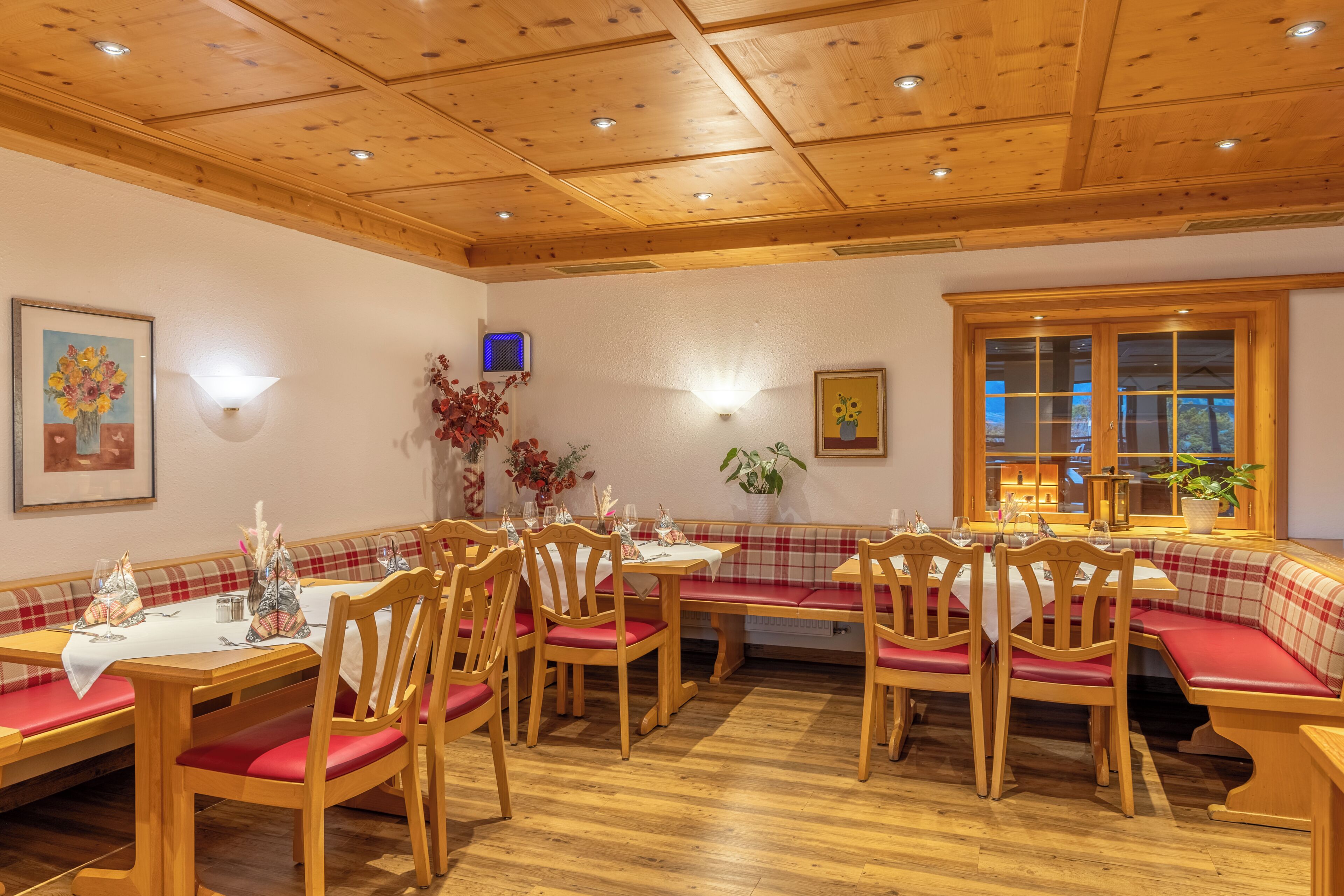 Un comedor con mesas y bancos de madera, un techo con iluminación empotrada y una ventana con vistas.