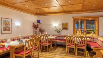 Un comedor con mesas y bancos de madera, un techo con iluminación empotrada y una ventana con vistas.