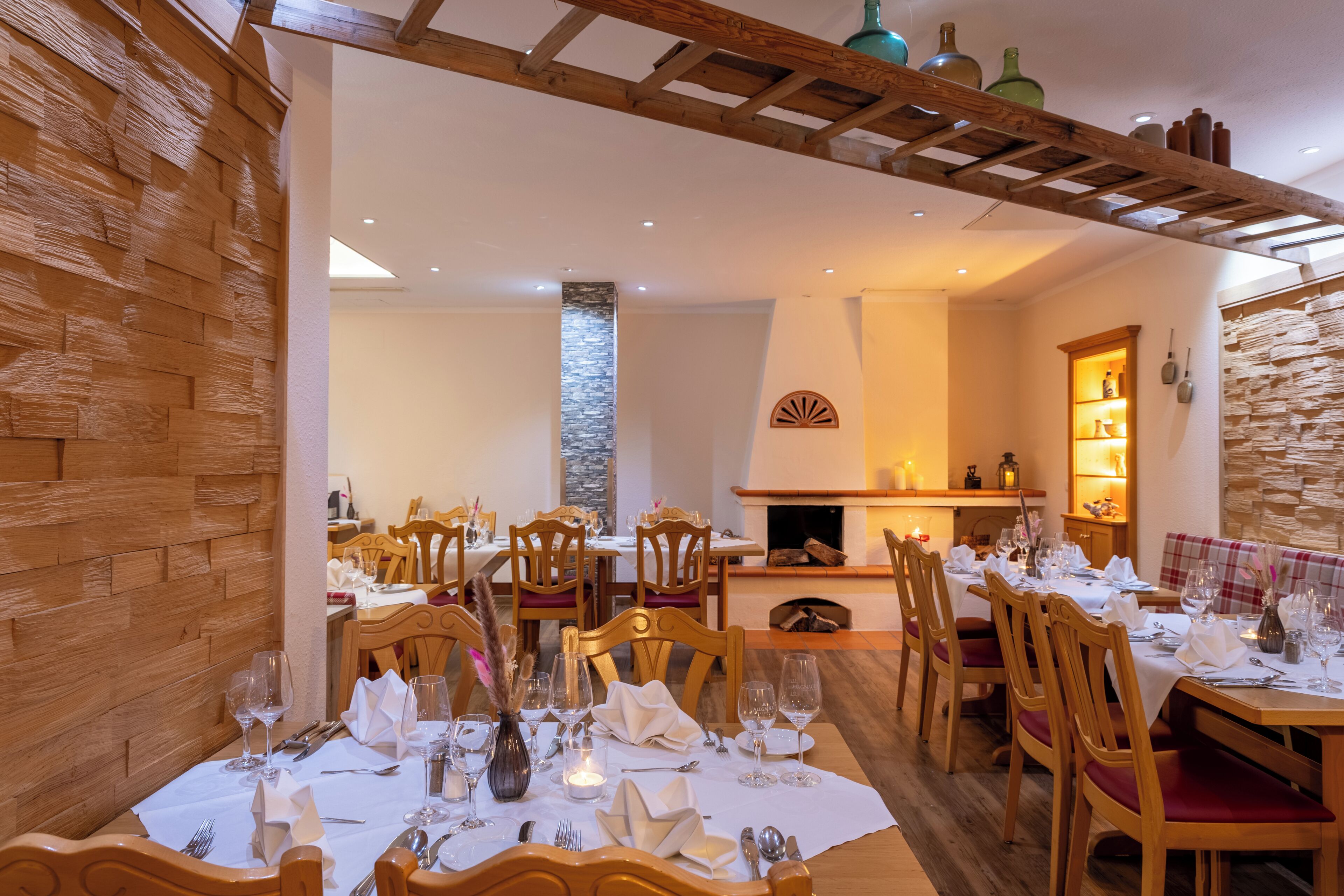Un comedor con mesas y sillas de madera, un pilar de piedra y una chimenea.