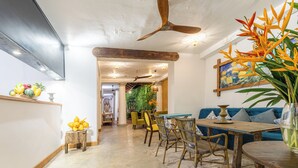 A room with a ceiling fan, a dining table with chairs, a sofa, and a large plant. - Parawa House (Galle)