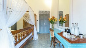 A bedroom with a four-poster bed, a vanity with toiletries, and a mirror. - Parawa House (Galle)
