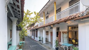 A narrow street with buildings on either side, outdoor seating, and potted plants. - Parawa House (Galle)