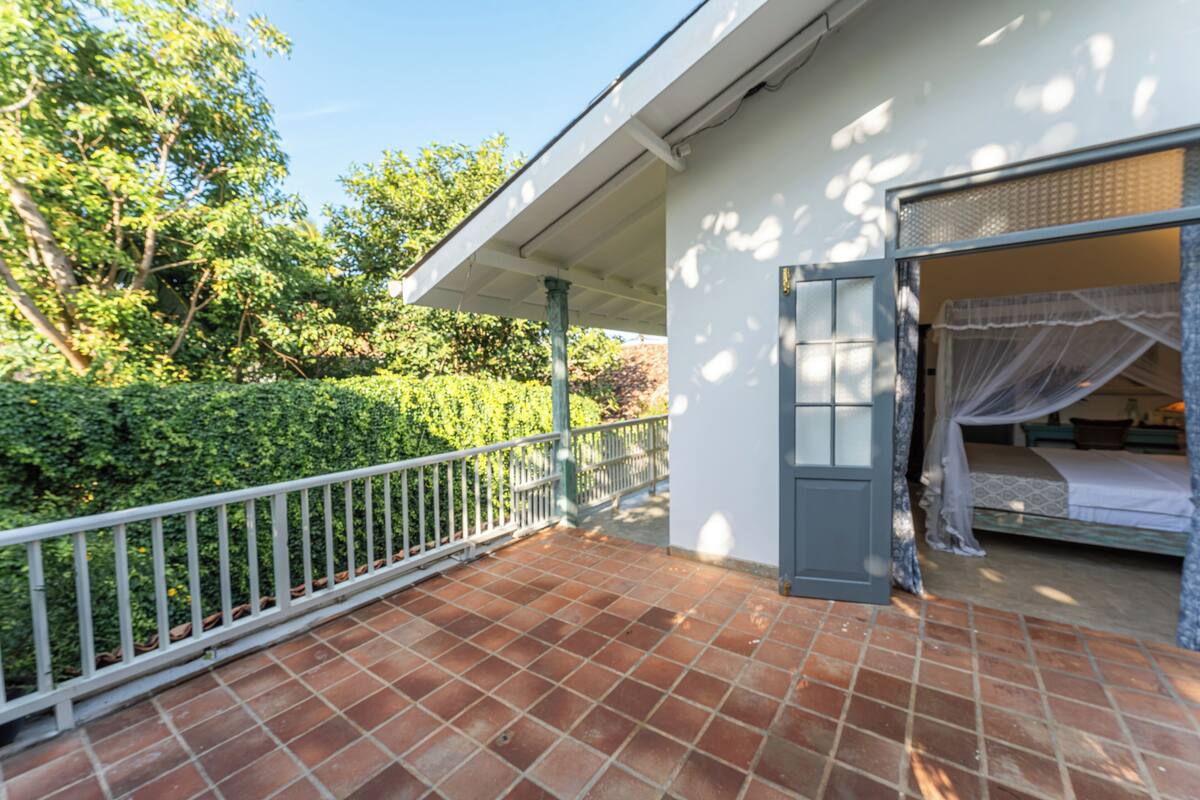 A balcony with a tiled floor, a white railing, and a bed with a canopy.