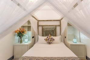 A bedroom with a canopy bed, a decorative headboard, bedside tables with lanterns, and a vase with flowers. - Parawa House (Galle)
