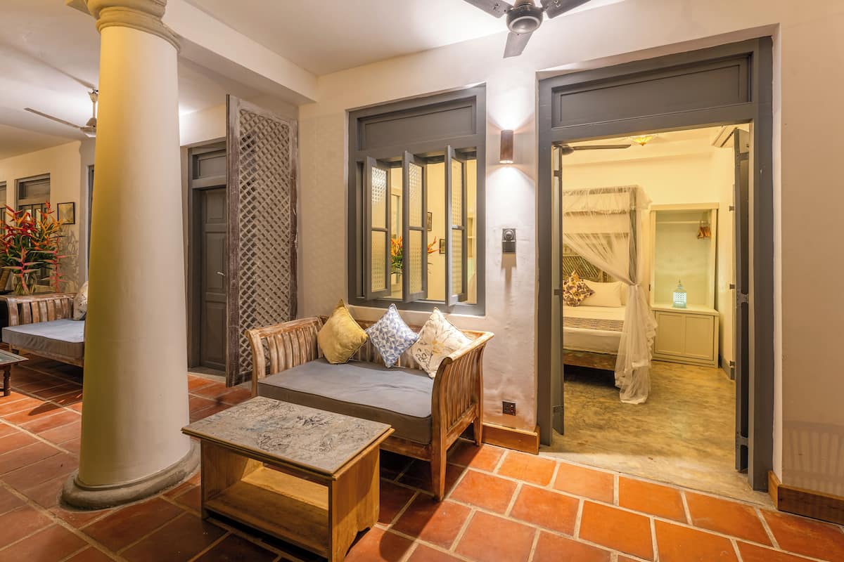 A hotel lobby with a sofa, a table, a pillar, and a doorway leading to a bathroom.