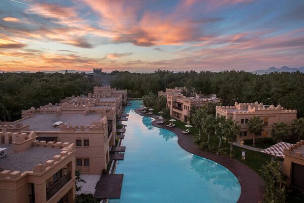 A resort with a swimming pool, multiple buildings, and a mountainous backdrop.
