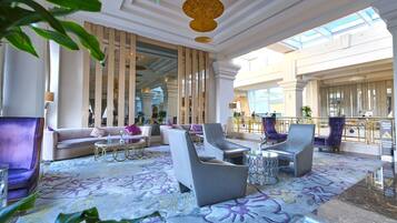 Eine großzügige Lobby mit modernen Möbeln, einem gemusterten Teppich und einer hohen Decke mit einem Chandelier.