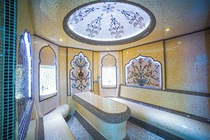 A bathroom with a large bathtub, a sink, and a bench.
