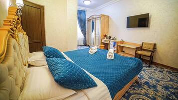 Une chambre d’hôtel avec un grand lit, un bureau, une chaise et un téléviseur fixé au mur.