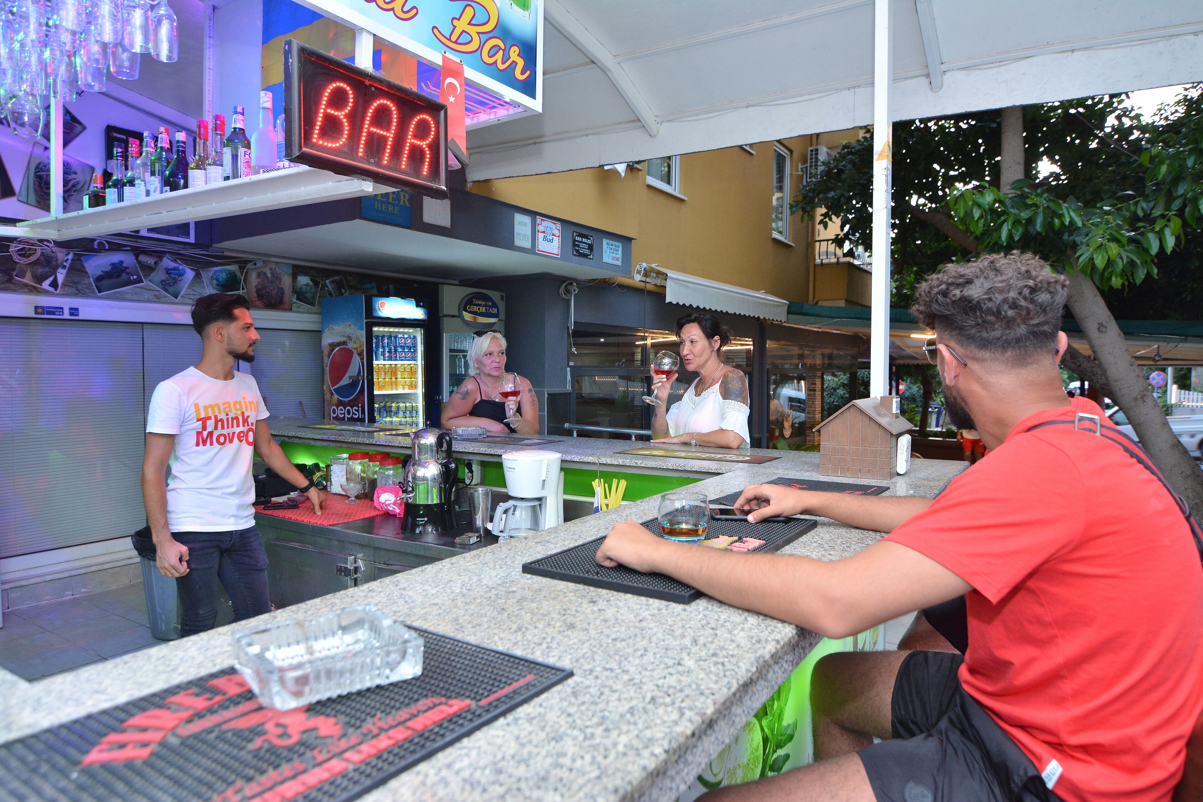 A bar area with a neon sign, a counter, and a seating area.