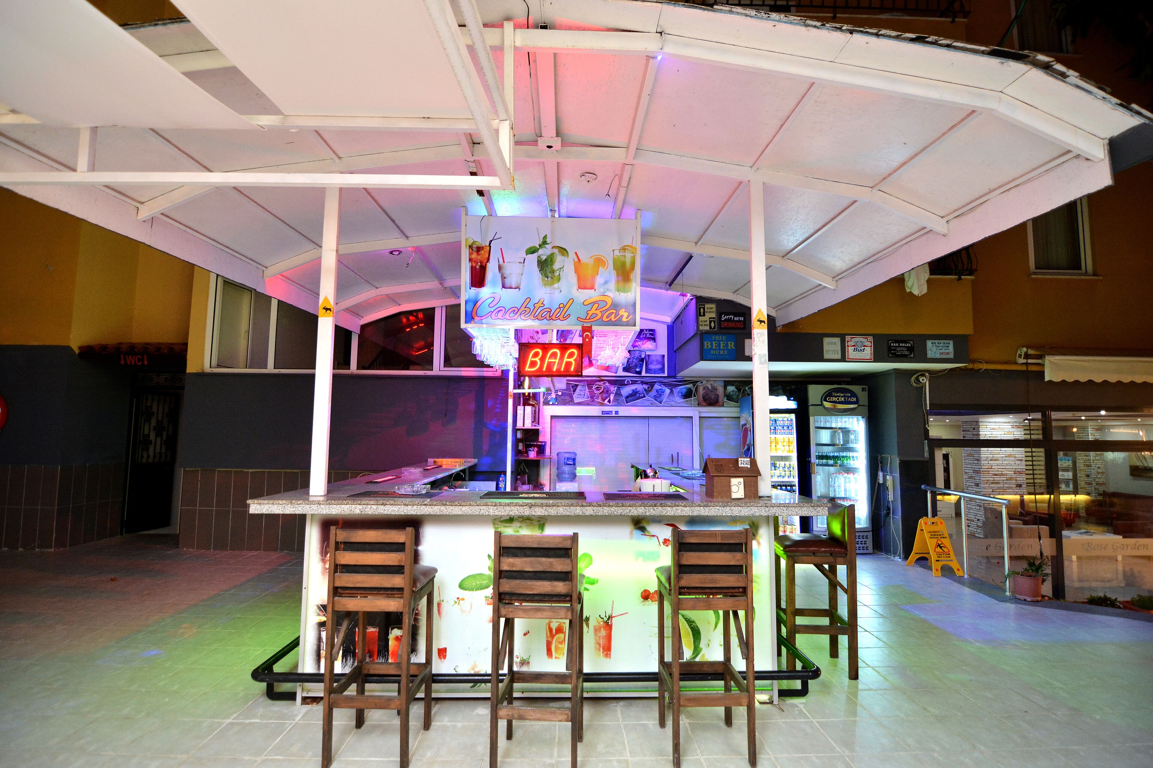 A bar with a neon sign, bar stools, and a counter.
