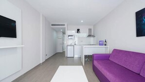 A modern apartment with a kitchen, a white sofa, and a small dining area. - eó Corona Cedral (Mogan)