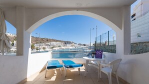 A balcony with a pool, blue lounge chairs, a small table, and a sign for 'Eco Hotels'. - eó Corona Cedral (Mogan)