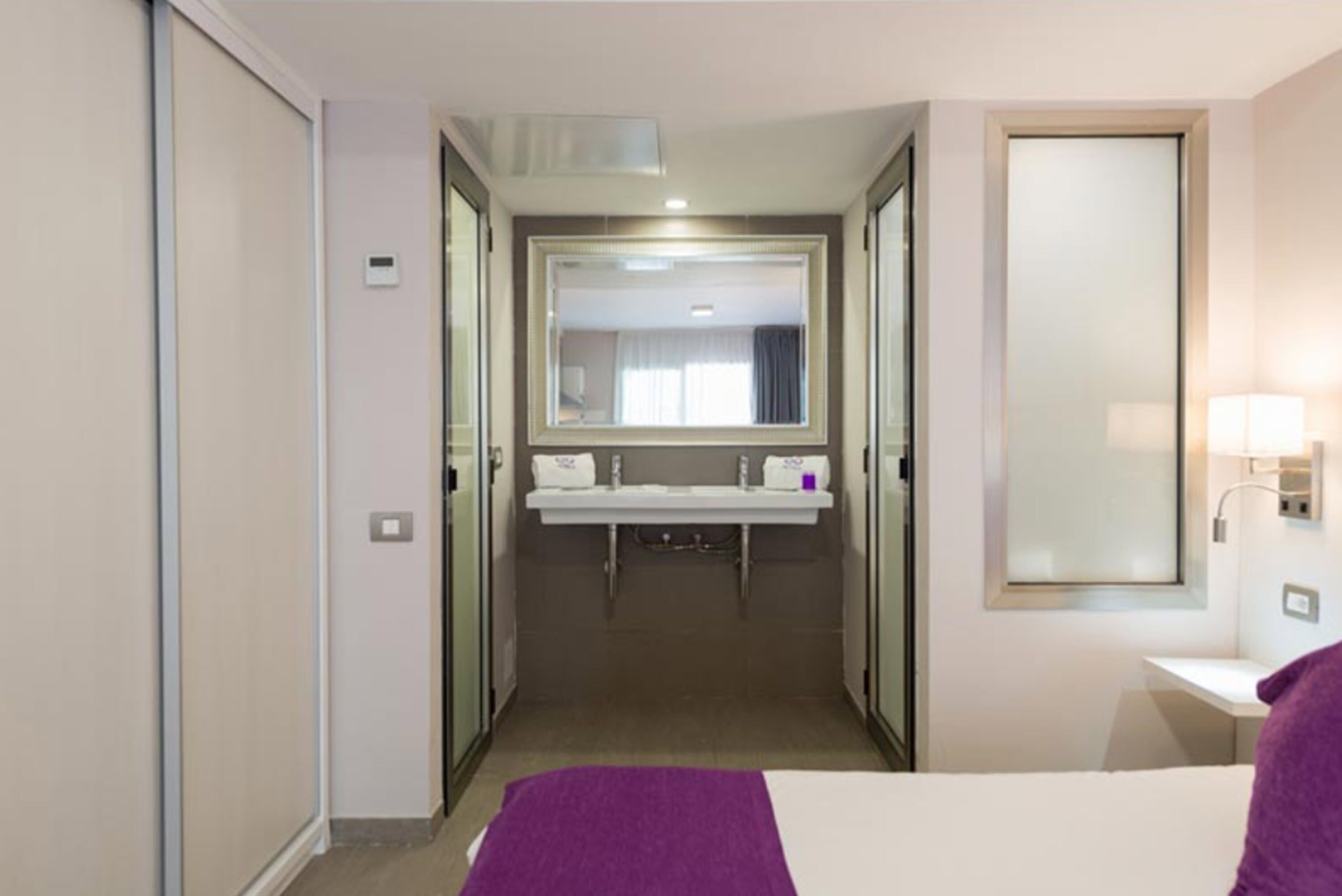 Une chambre d’hôtel avec un lit, une salle de bain avec un miroir et un lavabo.