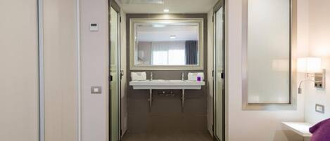 Une chambre d’hôtel avec un lit, une salle de bain avec un miroir et un lavabo.