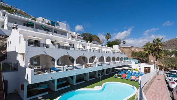 A hotel with a pool, outdoor seating, and a view of the surrounding landscape. - eó Corona Cedral (Mogan)