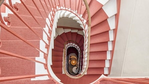 Uma escada em espiral com esquema de cores vermelho e branco, corrimãos de metal e um corrimão central.