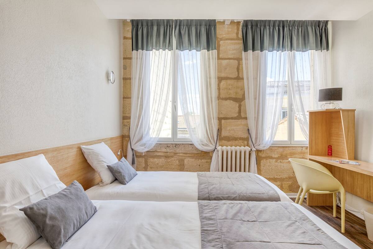 Une chambre avec deux lits, un bureau, une chaise et un radiateur.