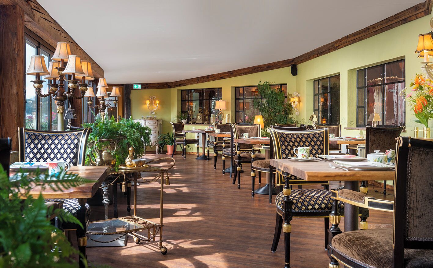 A restaurant with wooden floors, multiple tables and chairs, and large windows.