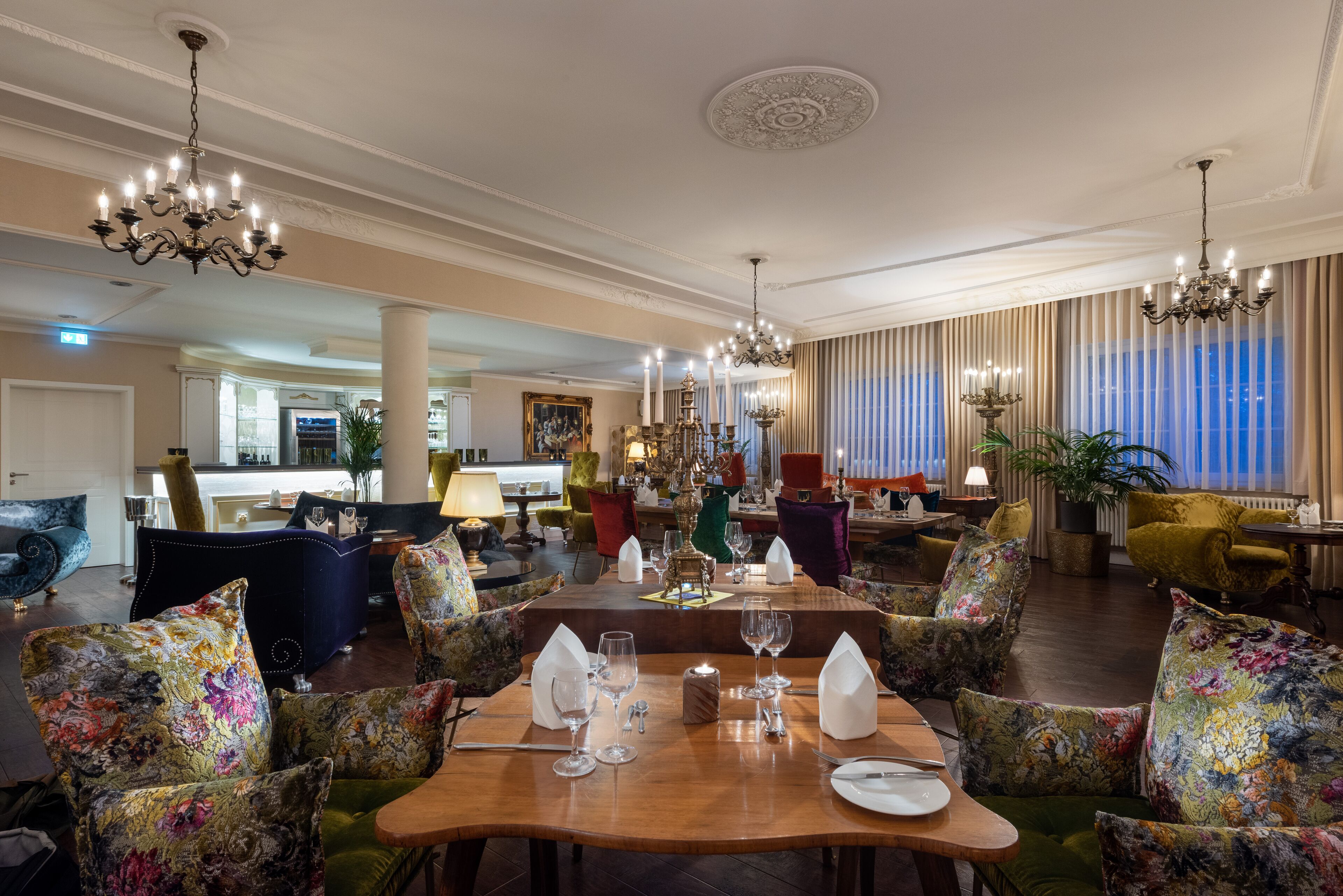A dining area with a wooden table set for four, surrounded by floral-patterned chairs.